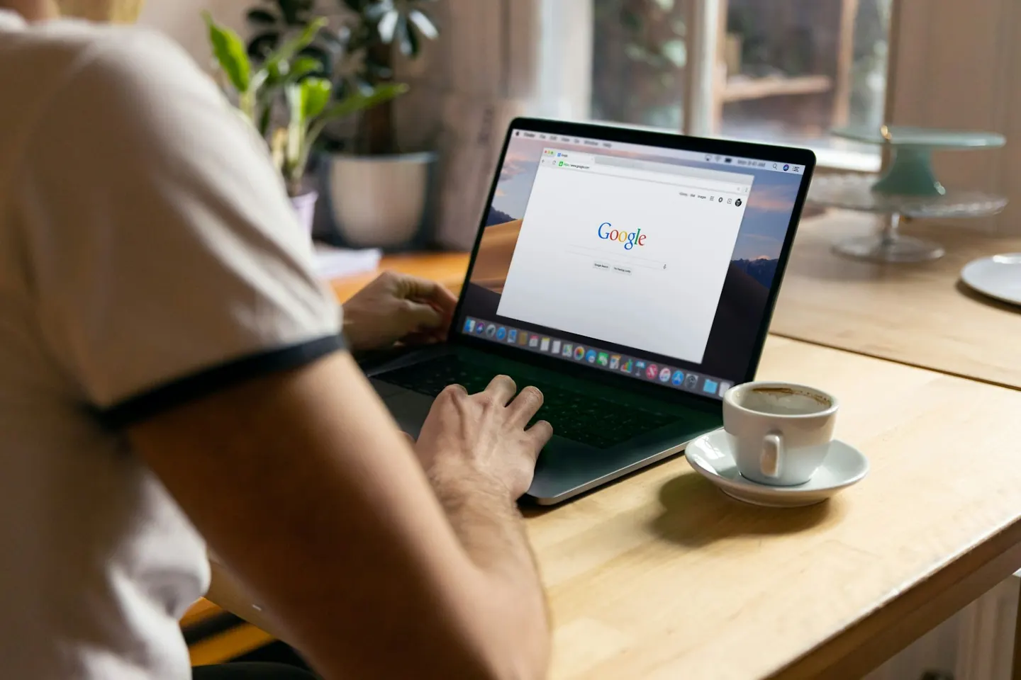 Google open on a laptop beside a cup of coffee