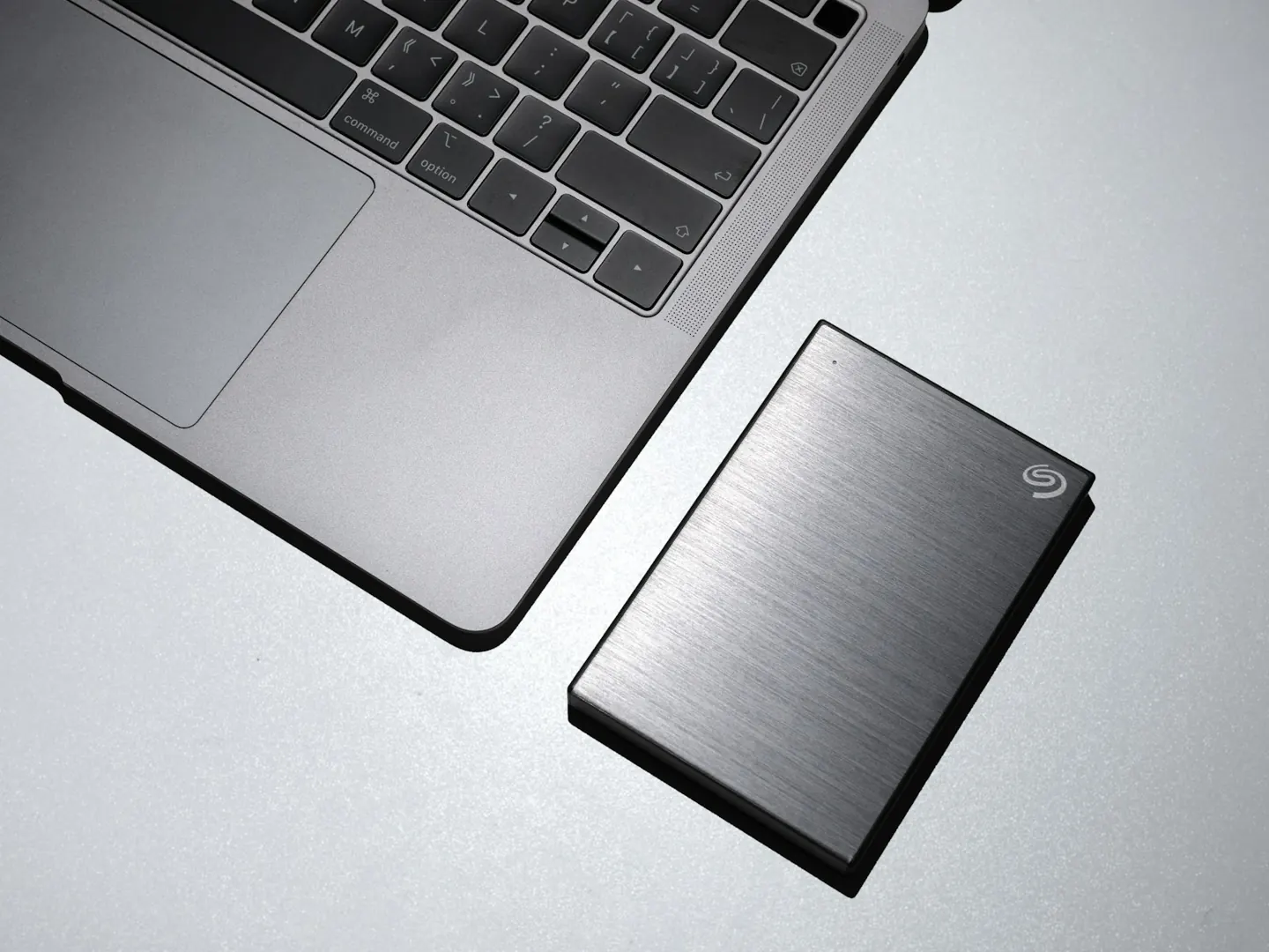 A laptop next to an external backup drive