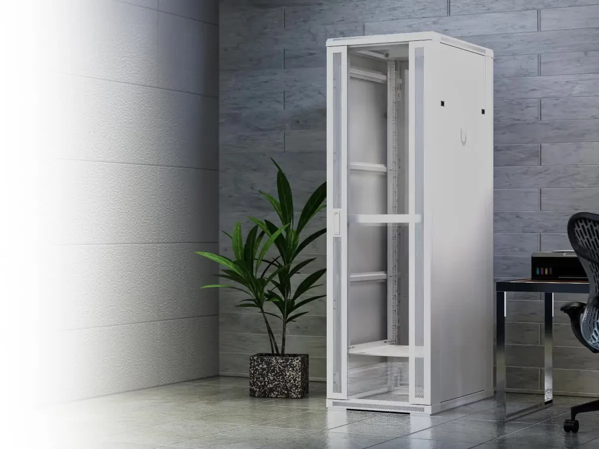 A UniFi rack cabinet in an office corner beside a potted plant