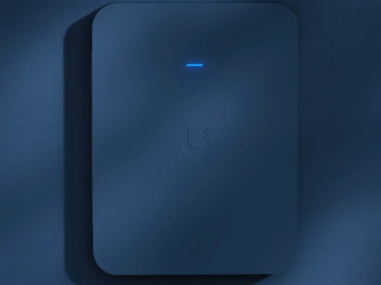 A UniFi wall access point on a navy blue wall